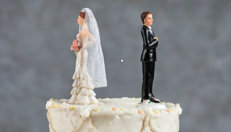 Une mariée en figurine tournant le dos au marié sur un gâteau de mariage